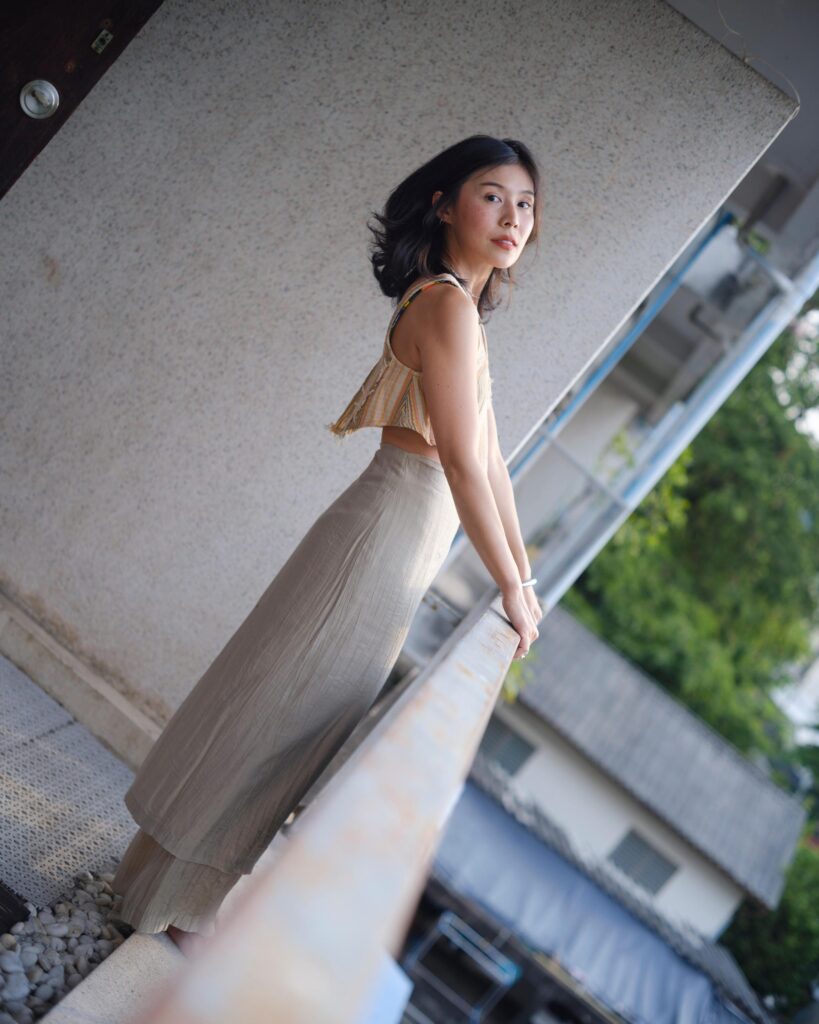 Pahparn Sirima leaning over a balcony railing, photographed from above in Bangkok.