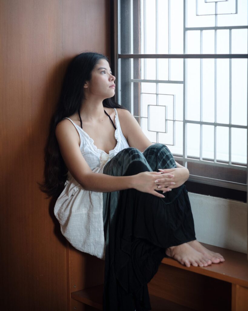 Pavee Vaidyanond seated beside a patterned window grille in Bangkok.