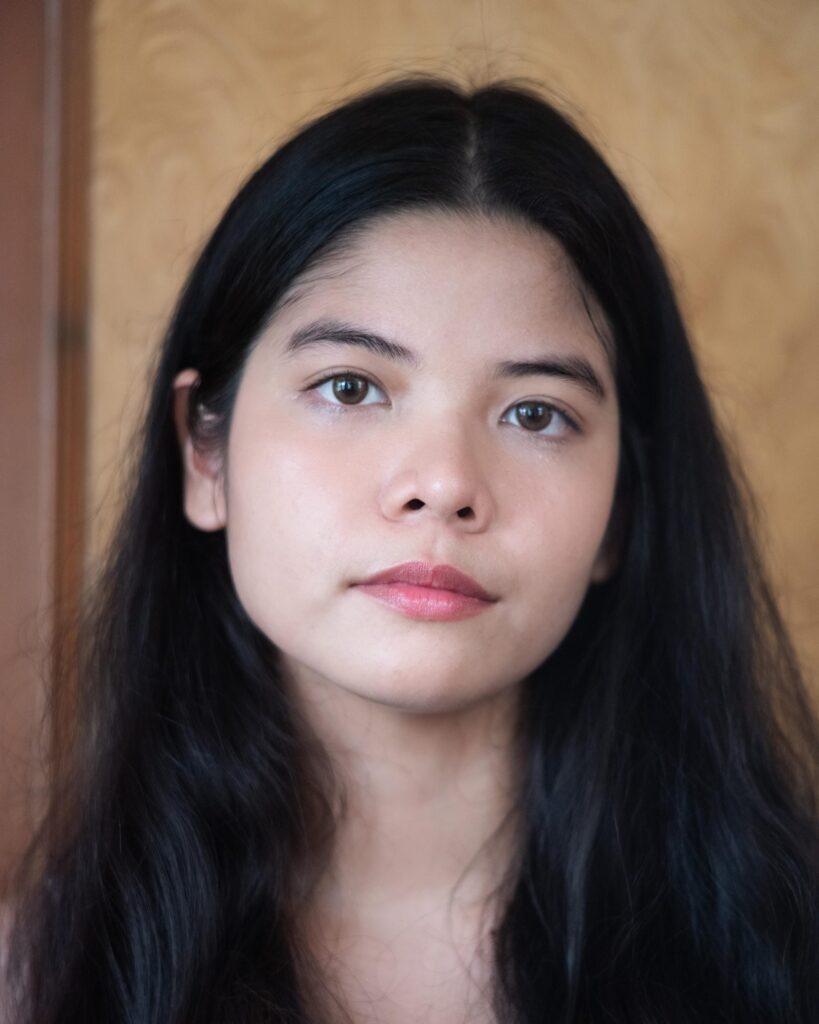 Close portrait of Pavee Vaidyanond against a warm-toned wall in Bangkok.