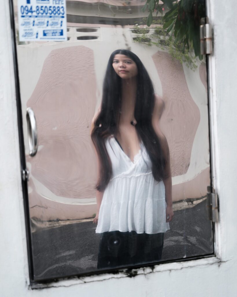 Pavee Vaidyanond reflected in a roadside mirror in Bangkok.