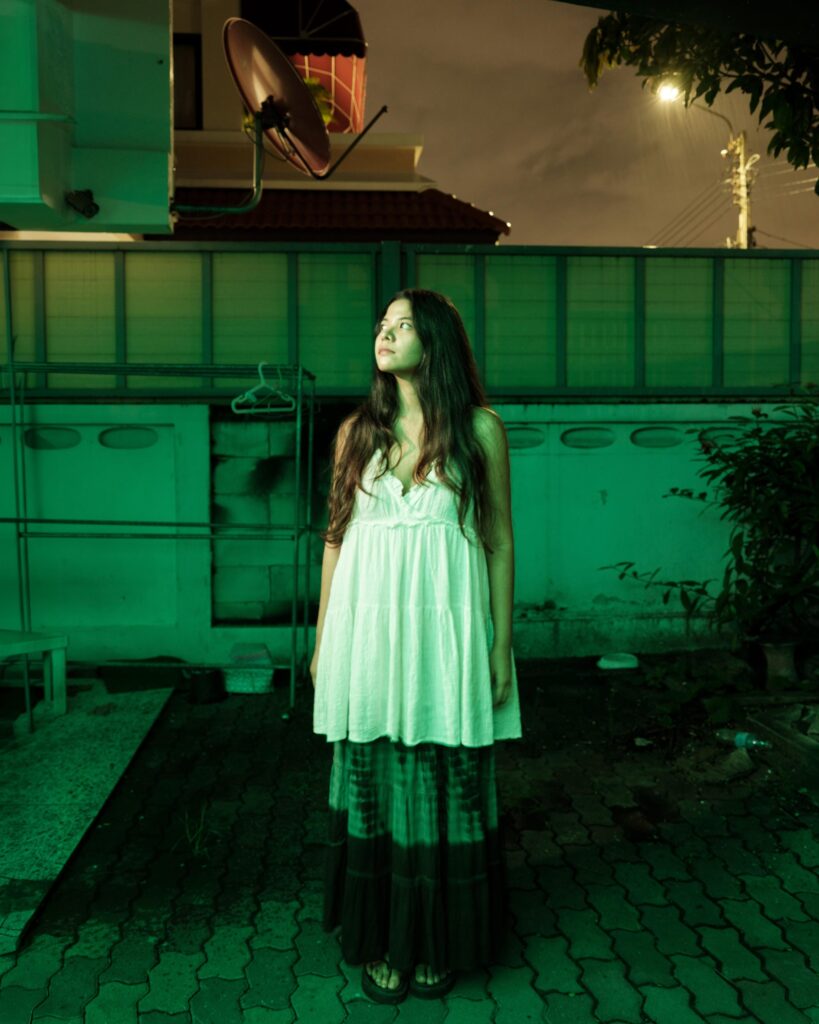 Pavee Vaidyanond outside her Bangkok home under green light at night.