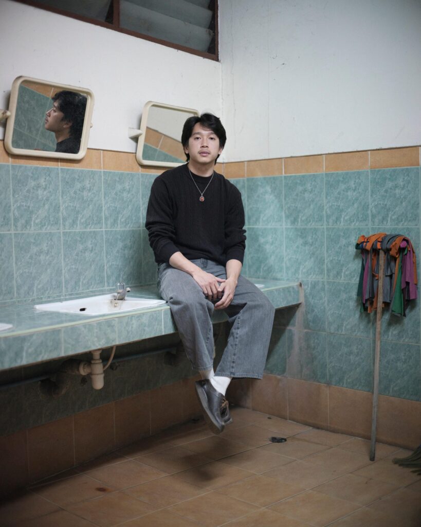 Peerapon Boonthep seated on a tiled washbasin inside Artcade Gallery in Phayao.