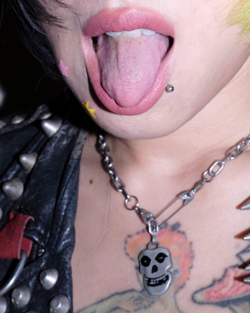 Close-up of Sadsadgirl's tongue piercing and skull pendant during her Samut Sakhon portrait session.