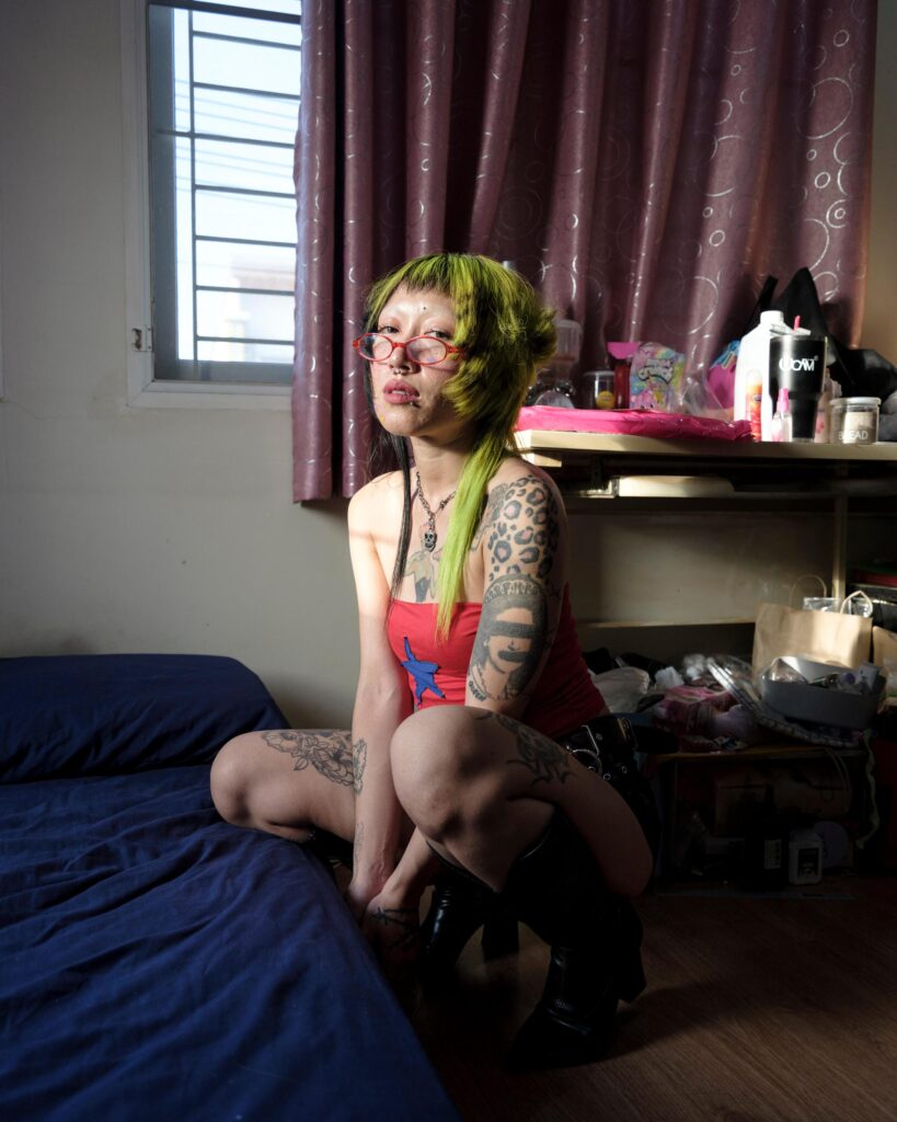 Pemika Wongsurakarn (Sadsadgirl) seated on a bed with a dog at home in Samut Sakhon.