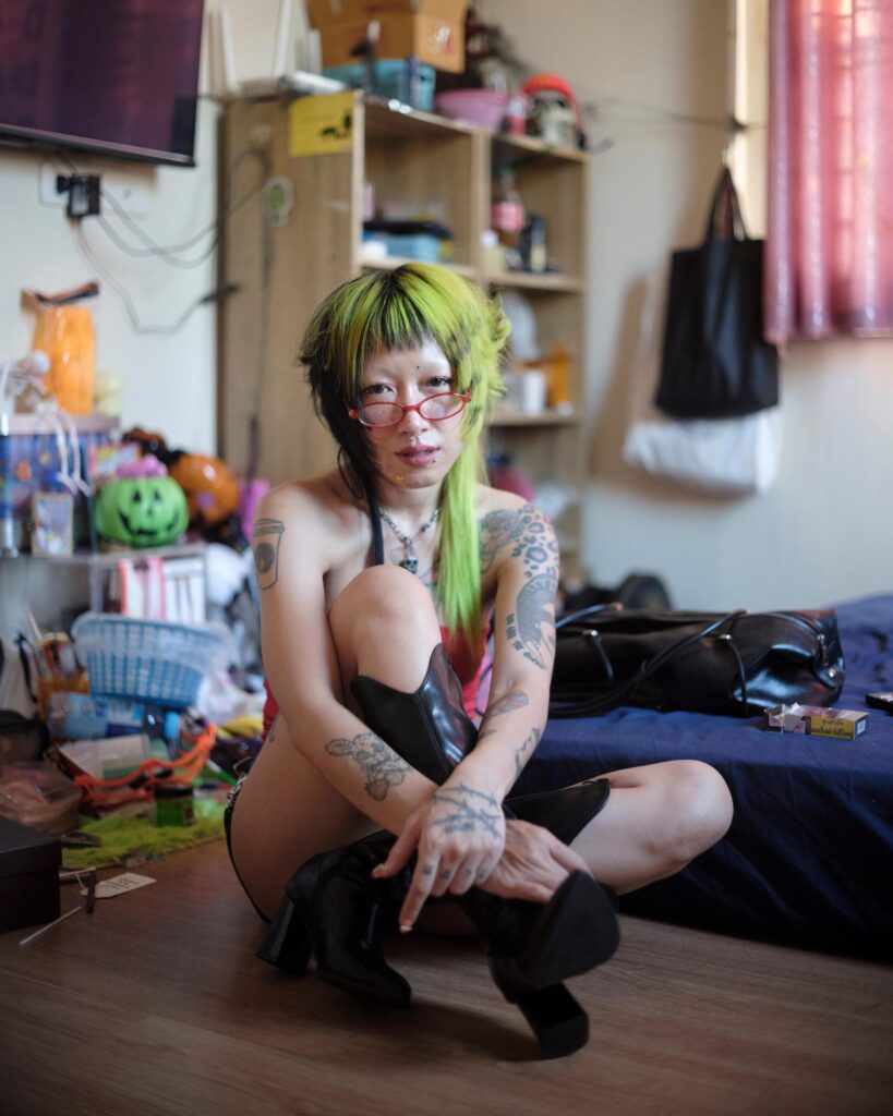 Pemika Wongsurakarn (Sadsadgirl) crouching beside a bed at home in Samut Sakhon.