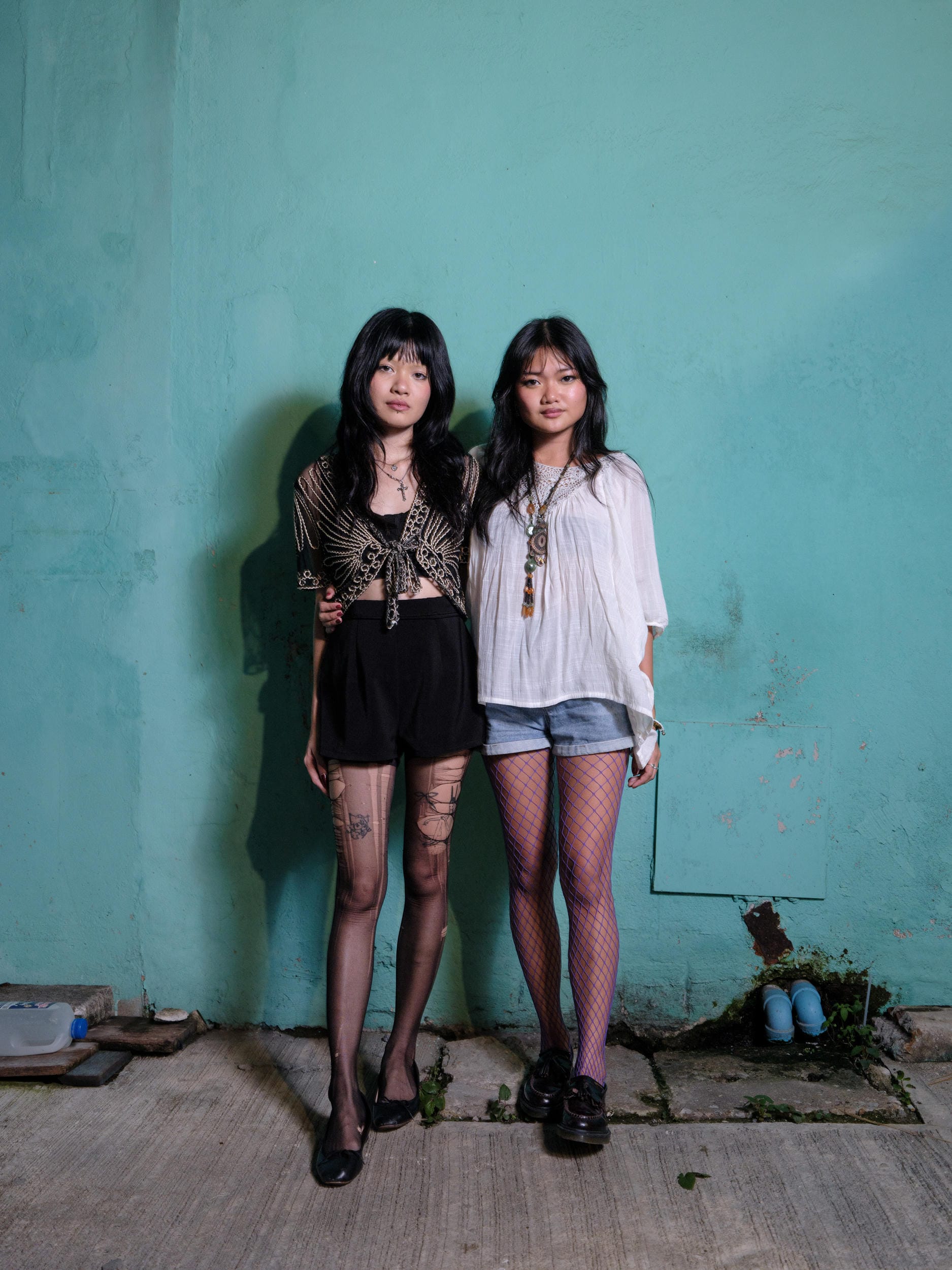 Phoenixe and Klein standing together against a turquoise wall in Bangkok.