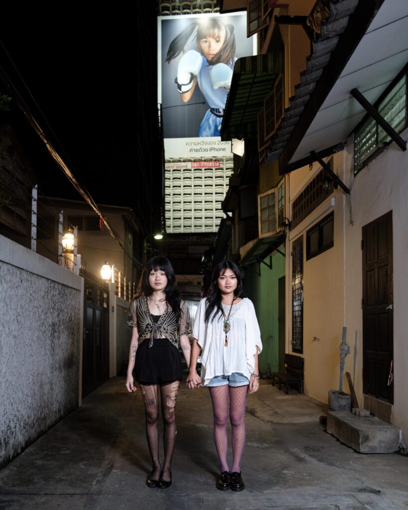 Phoenixe and Klein walking together in a Bangkok alley at night.