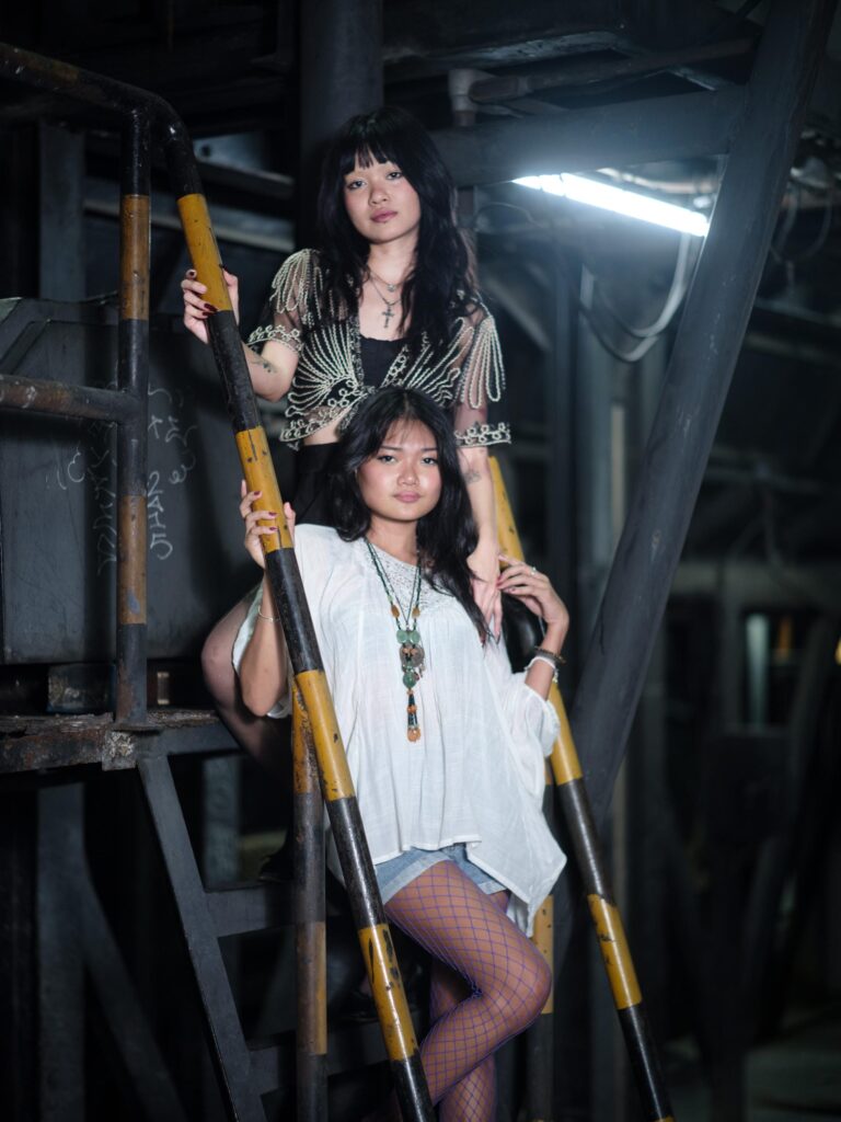 Phoenixe and Klein posing together on a yellow ladder in Bangkok.