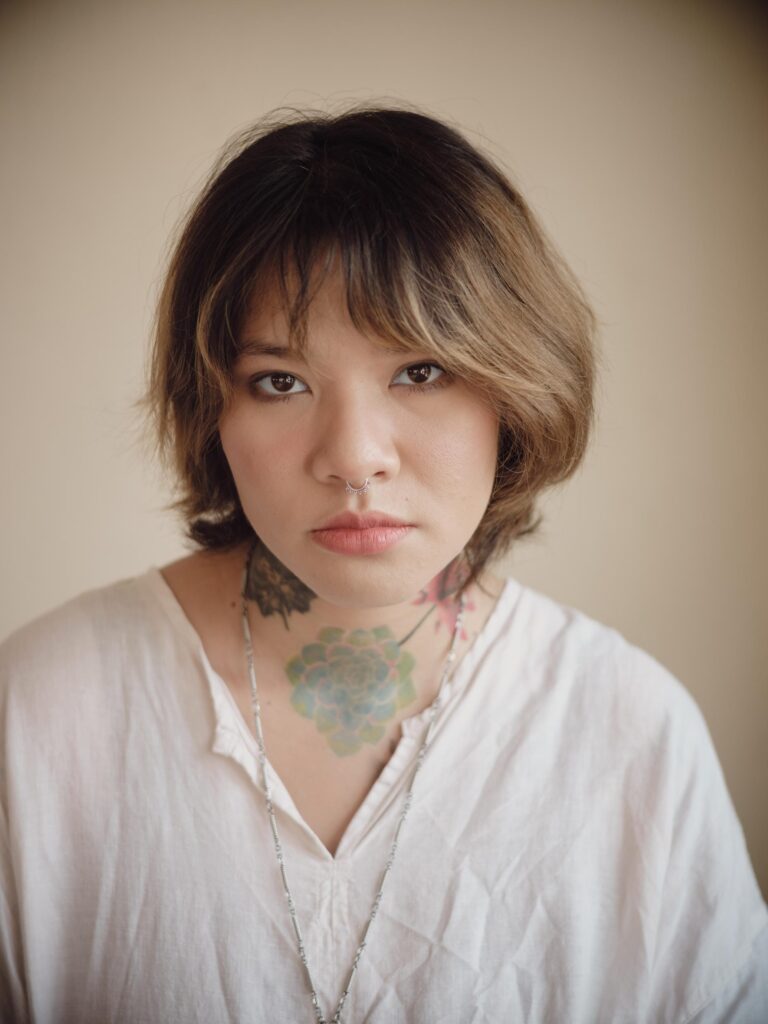Close portrait of Ploypim wearing a white shirt in her Bangkok studio.