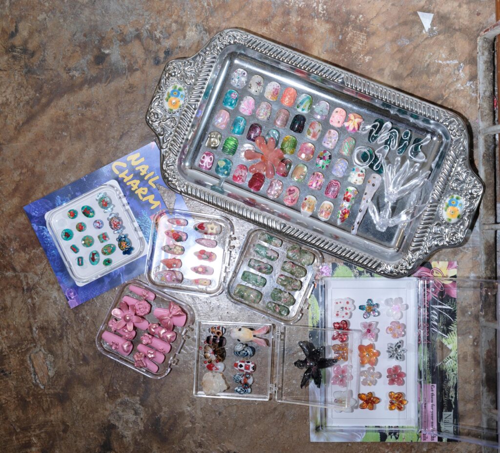 Colourful nail-art samples arranged in trays on the Q3Q Community studio floor in Bangkok.