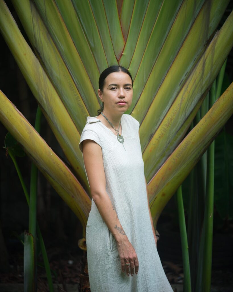 Rosalia Engchuan standing in front of large green palm stems in Bangkok.