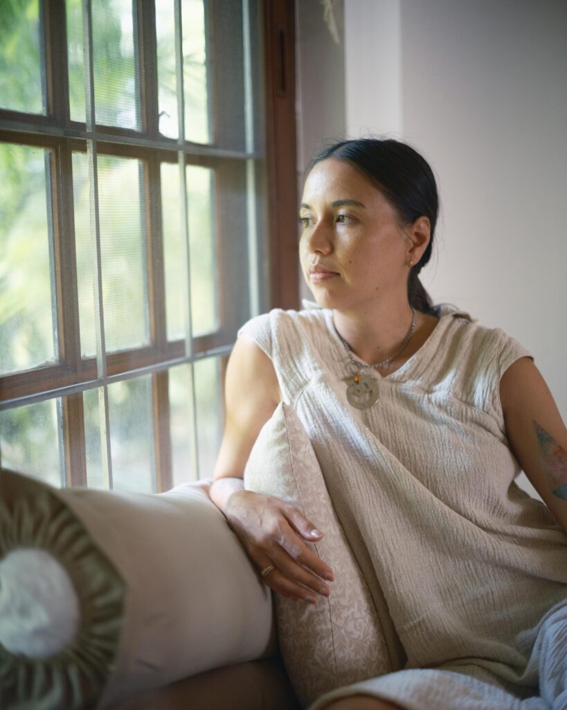 Rosalia Engchuan seated beside a wooden-framed window at home in Bangkok.