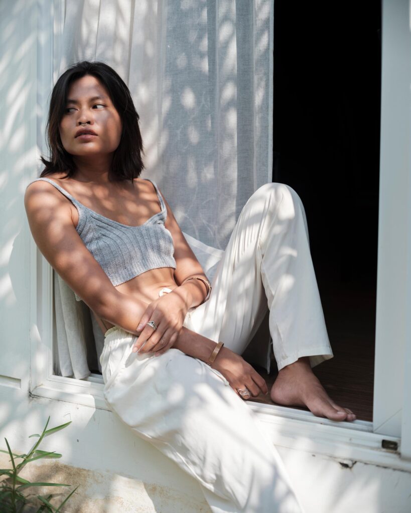 Sacha Piisasha seated on a window ledge in sunlight at home in Nonthaburi.