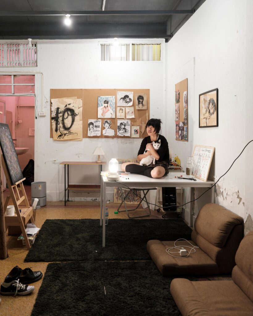 Sandee seated on a worktable inside her art-filled Bangkok studio.