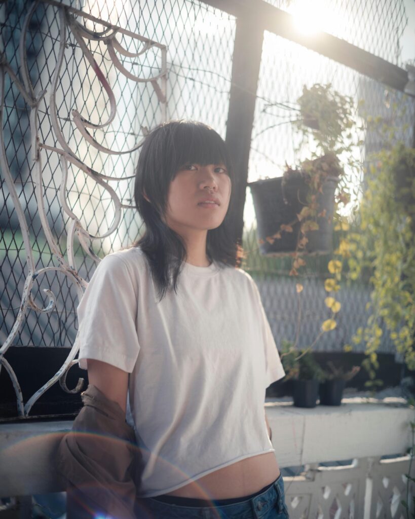 Sandee seated beside a drawn-on window in warm evening light in Bangkok.