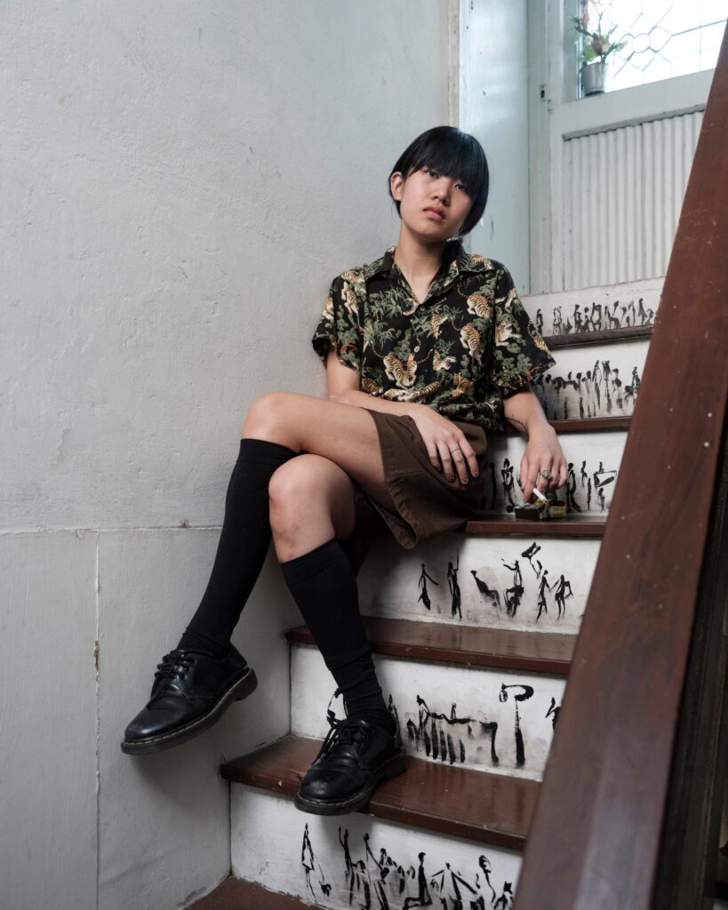 Sandee seated on a staircase with writing on the steps in Bangkok.
