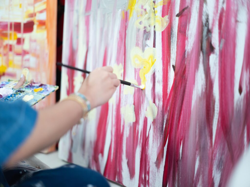 Tamruja Dharmasaroja's hand painting yellow details onto a red-and-white canvas in Bangkok.